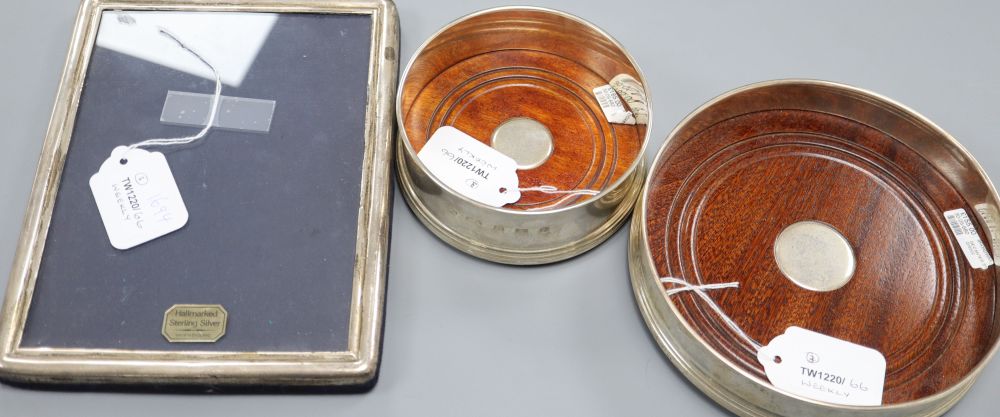 A large modern silver decanter coaster, a similar smaller coaster and a sterling silver photograph frame (3)